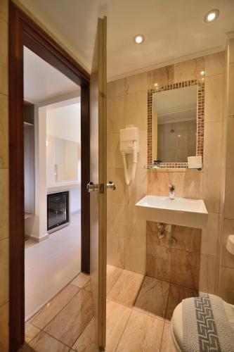 a bathroom with a sink and a toilet and a mirror at Falassarna Hotel in Chania