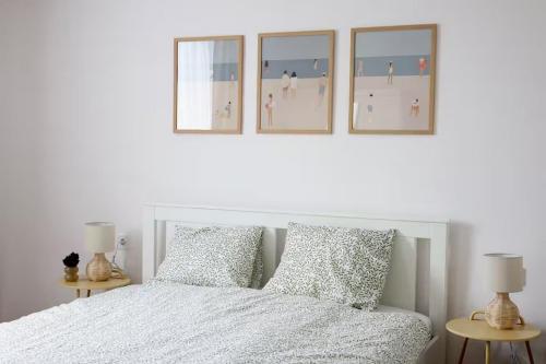 a bedroom with a white bed with four pictures on the wall at Dottygal Fiumei UIA in Balatonboglár