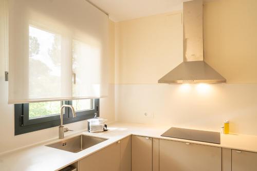 a kitchen with white cabinets and a sink and a window at Majordoms Velo in Llambillas