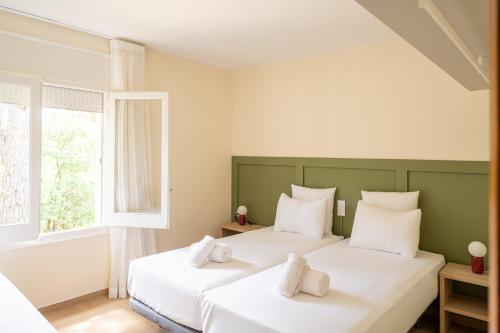 two white beds in a room with a window at Majordoms Velo in Llambillas