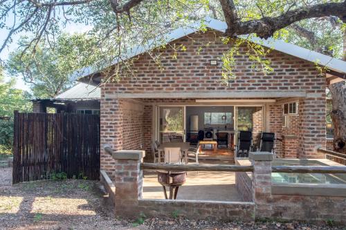 a brick house with a patio with a table and chairs at Kruger's Retreat & Rest in Marloth Park