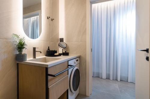 a bathroom with a sink and a washing machine at NAEMA Seafront Living 2BR Suite in Anissaras