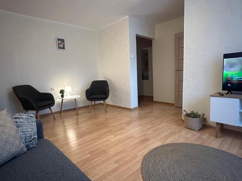 a living room with a couch and two chairs and a television at Welcome Valmiera in Valmiera