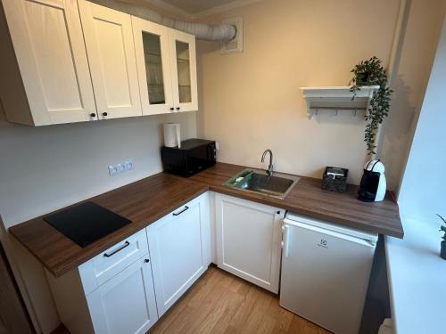 a small kitchen with white cabinets and a sink at Welcome Valmiera in Valmiera