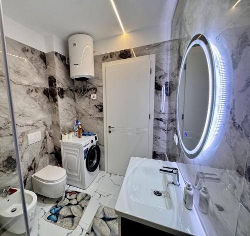 a bathroom with a sink and a toilet and a mirror at Marbel Sea View in Shëngjin