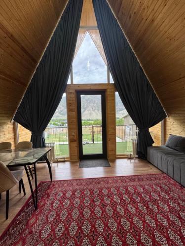 a living room with a large window and a red rug at Eldos_Kolsai in Saty