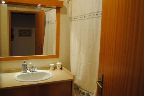 a bathroom with a sink and a mirror and a shower curtain at Vilamoura Apartment in Vilamoura