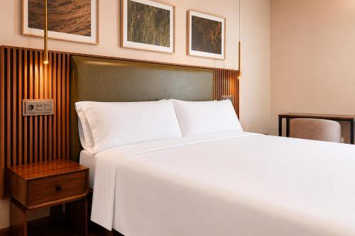 a bedroom with a large white bed and a table at Hotel El Nogal in Peligros