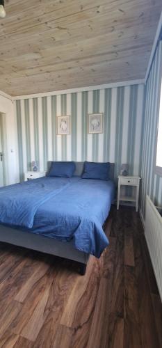 a bedroom with a blue bed and a wooden ceiling at Michel-Inn-Your Scandinavian Escape! in Faggemåla