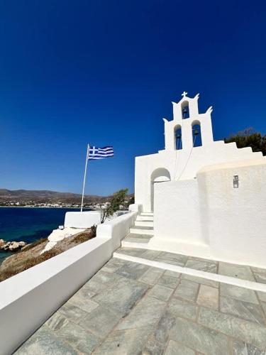 a white church with a flag next to the water at Artistic Villa Aqua Ios in Ios Chora