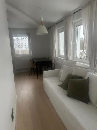 a living room with a white couch and two windows at Studio Sleeps 2 Sollentuna centre in Sollentuna