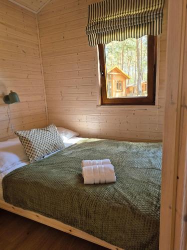 a bed in a log cabin with a window at Pine House Domek 22 in Borsk