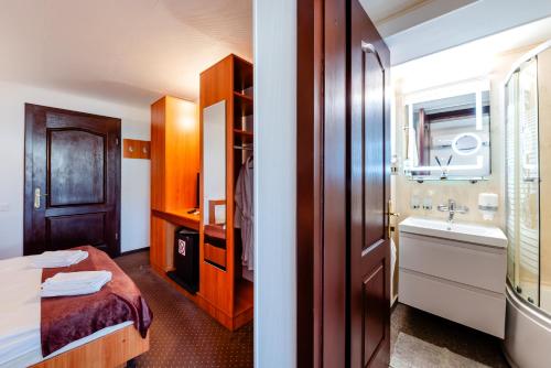 a hotel room with a bathroom with a bed and a sink at Hotel Regal in Costinesti