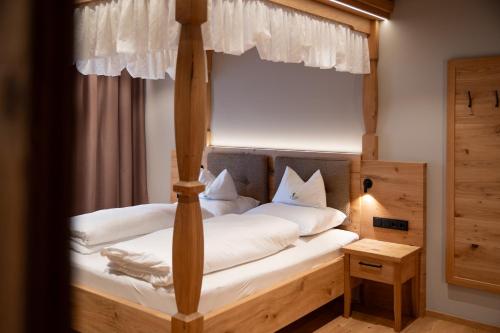 a bedroom with a canopy bed with white pillows at Hotel Hochfilzer in Ellmau