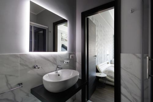 a bathroom with a white sink and a mirror at La Palazzata Urban Suites in Messina