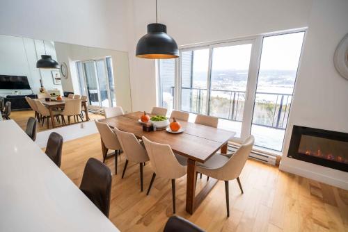 a dining room with a table and chairs and a fireplace at 403 - Luxury Condo - Incredible View & Pool in Baie-Saint-Paul