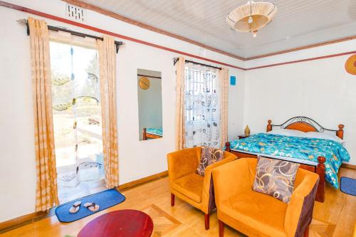a bedroom with a bed and a chair and a window at Chakruok Gardens, Hawi in Bondo