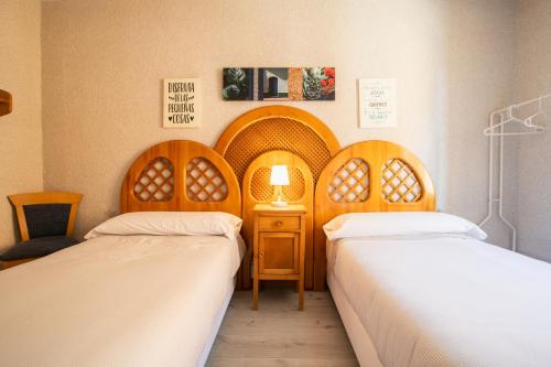 a room with two beds and a table with a lamp at Acogedora casa histórica en Segovia by CABANA Rentals in La Lastrilla