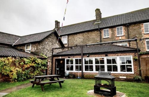 ein Haus mit einem Picknicktisch davor in der Unterkunft The Fox and Maple in Wickwar