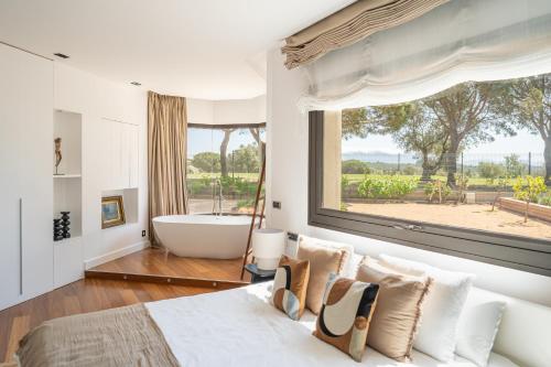 a bedroom with a tub and a bed and a window at Majordoms Golf Peralada in Peralada