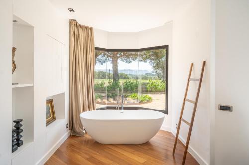 a bath tub in a bathroom with a large window at Majordoms Golf Peralada in Peralada