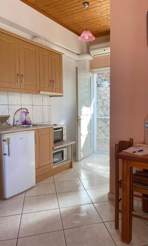 a kitchen with white appliances and a table and a door at Albatros rooms in Vathi
