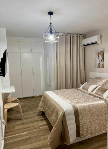 a bedroom with a bed and a chandelier at SOLyMAR in Garrucha