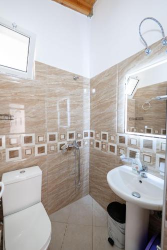 a bathroom with a white toilet and a sink at Nino's rooms in Ksamil