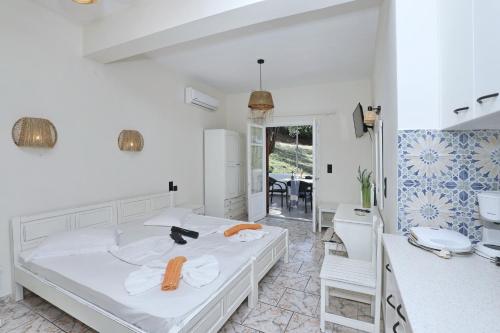 a white bedroom with a bed and a chair at Albatros in Skopelos Town