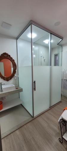 a glass shower stall with a sink and a mirror at Pousada Buona Serata in Bento Gonçalves