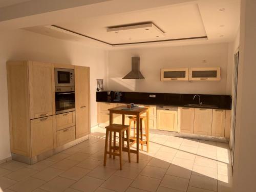 a kitchen with wooden cabinets and a table and stools at Villa pieds dans l'eau, magnifique terrasse face à la mer in Zarzis