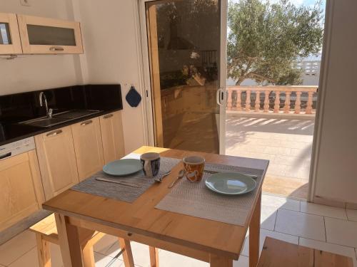 a kitchen with a wooden table with plates and mugs on it at Villa pieds dans l'eau, magnifique terrasse face à la mer in Zarzis