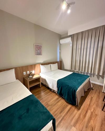 a hotel room with two beds and a window at Real Hotel in Sete Lagoas