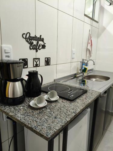 a kitchen with a counter top with a coffee pot and plates at Próximo a UFV 950m, prédio muito tranquilo in Viçosa