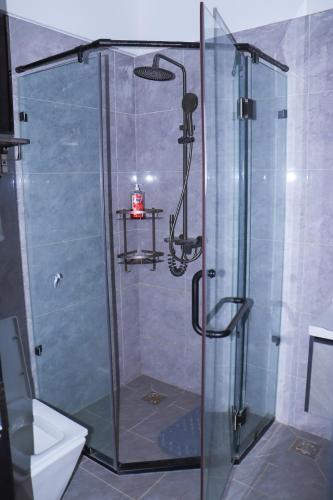 a shower with a glass door in a bathroom at Malkia Exquisite Homes in Nairobi