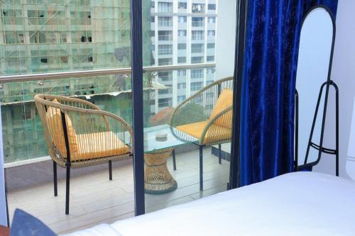 a bedroom with a balcony with two chairs and a table at Malkia Exquisite Homes in Nairobi