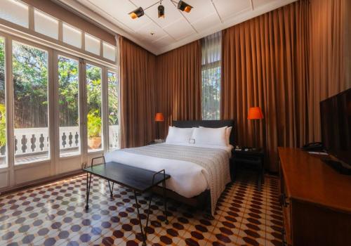 a bedroom with a bed and a tv and windows at The Henry Hotel Manila in Manila