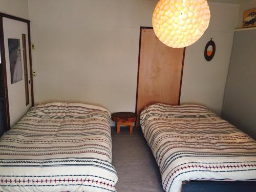 two beds in a small bedroom with a lamp at MEGANE HOUSE First floor All private in Rankoshi