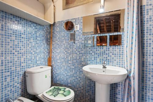 a blue tiled bathroom with a toilet and a sink at Buhardilla en centro histórico in Málaga
