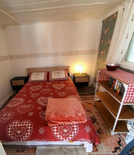 a bedroom with a red bed and a book shelf at Maison des Roses in Béalencourt