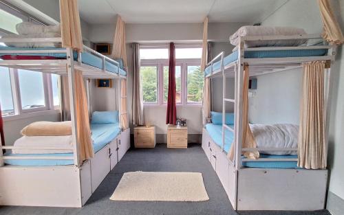 a room with four bunk beds with a window at Tag Along 2 0 Hostel Gangtok in Gangtok
