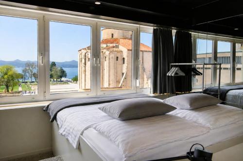 a bed in a room with a large window at Boutique Hostel Forum in Zadar