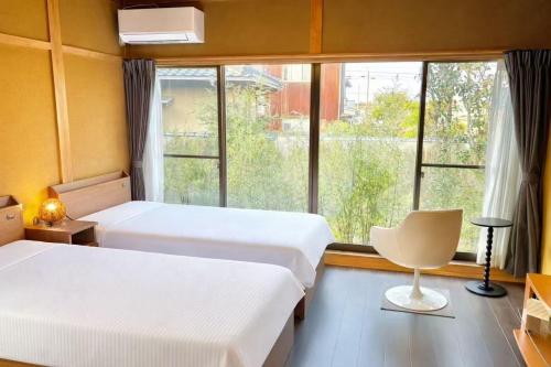 two beds in a room with a window and a chair at 結良house in Yura