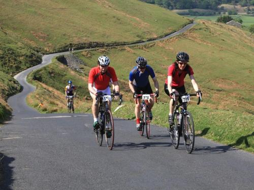 a group of people riding bikes down a road at Woodside B&B in Keswick