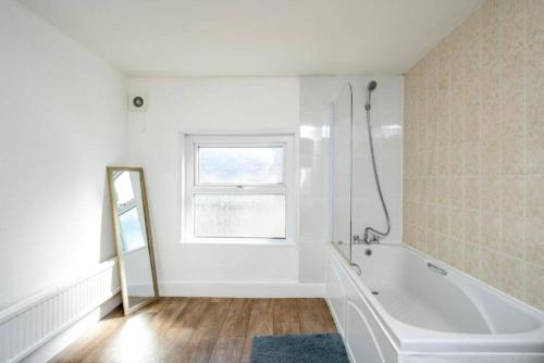 a white bathroom with a tub and a window at Central Stroud 3-Bedroom Flat with Fast WiFi in Stroud