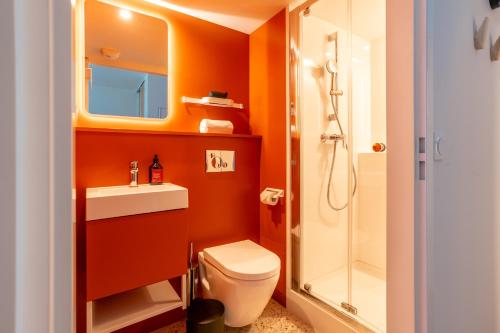 a bathroom with orange walls and a toilet and a shower at ECLA Genève Archamps in Archamps