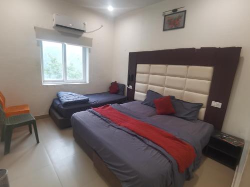 a bedroom with a bed and a couch and a window at Tira Hotel and Cafe in Rudraprayāg