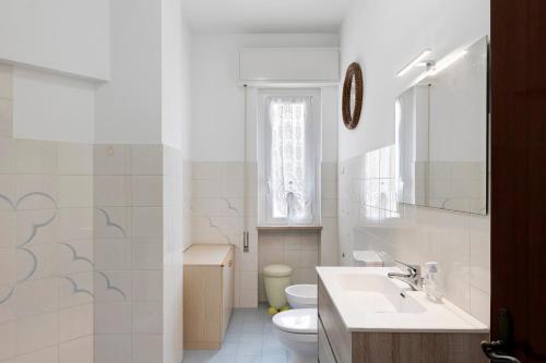 a white bathroom with a sink and a toilet at Isonzo Holiday Home - 2 bedrooms in Loano