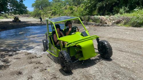Zwei Personen fahren in einem grünen Quad am Strand in der Unterkunft Frailin Merete in San Felipe de Puerto Plata