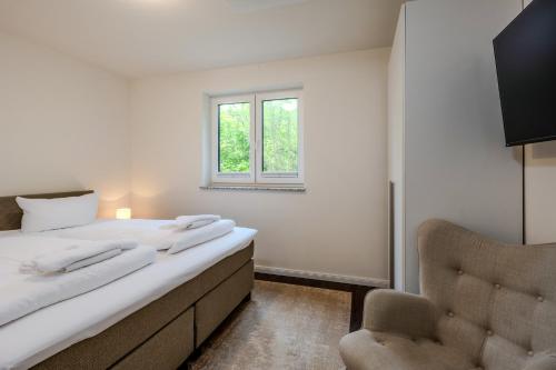 a bedroom with a bed and a chair and a window at Dünenquartier Apartment 24 in Zingst